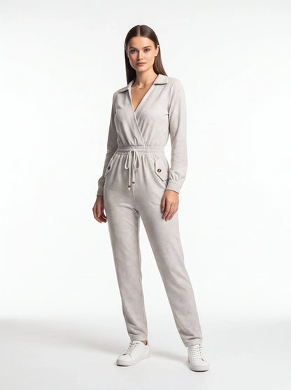 Jamota light gray jumpsuit with wrap-front neckline, elastic drawstring waist, and front pockets with buttoned flaps.