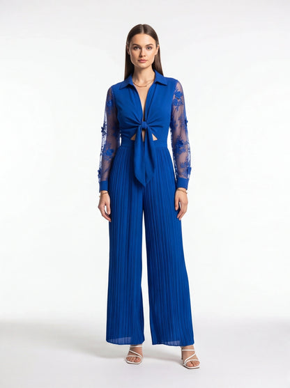 Jamota cobalt blue jumpsuit with sheer lace sleeves, deep V neckline, knotted front and wide pleated legs
