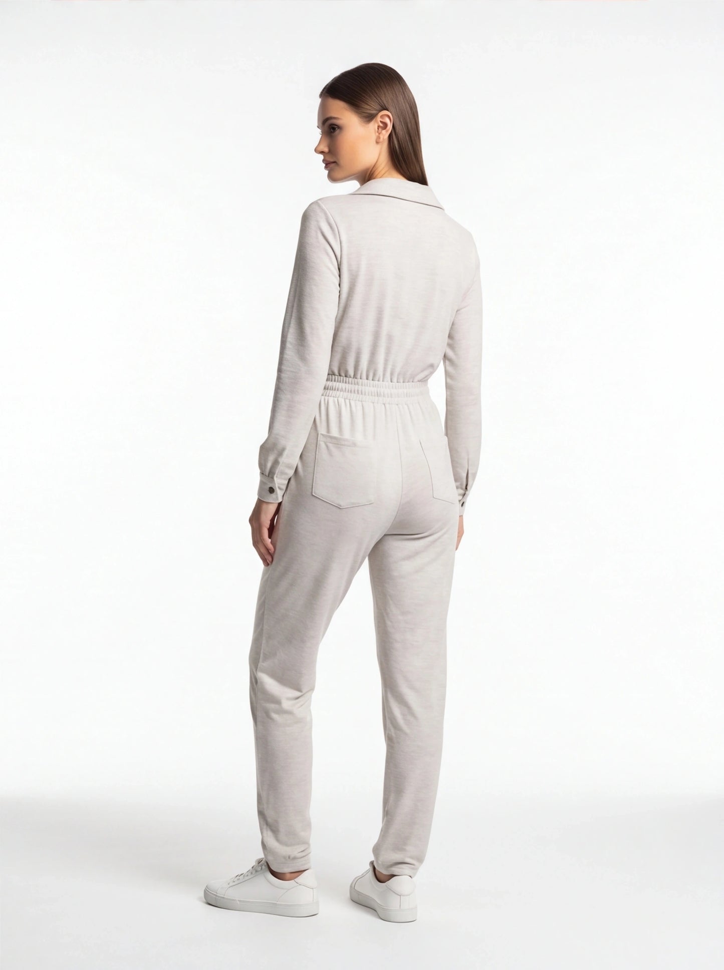 Jamota beige jumpsuit with long sleeves, elastic waistband and back pockets shown with white sneakers