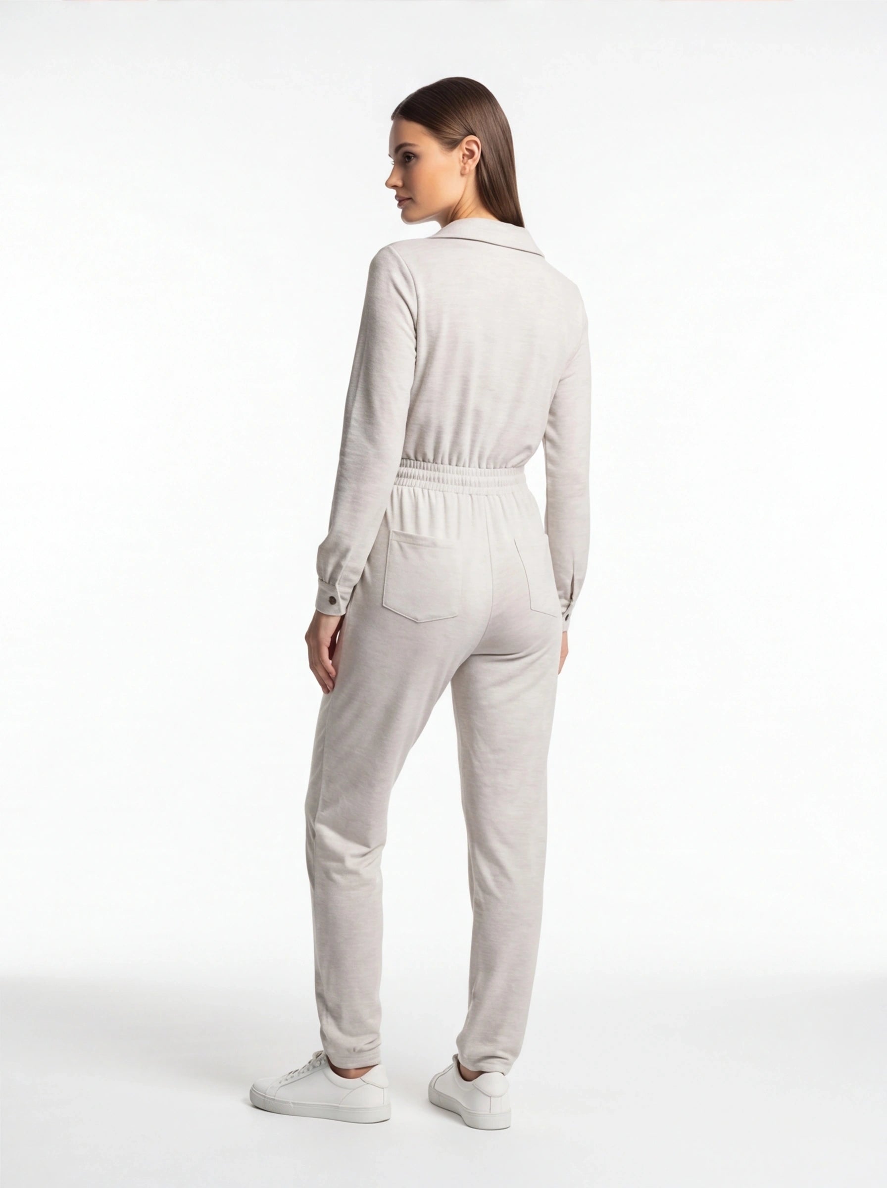 Jamota beige jumpsuit with long sleeves, elastic waistband and back pockets shown with white sneakers