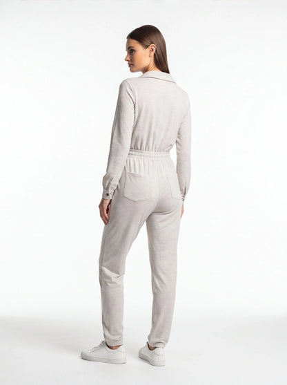 Jamota beige jumpsuit with long sleeves, elastic waistband and back pockets shown with white sneakers