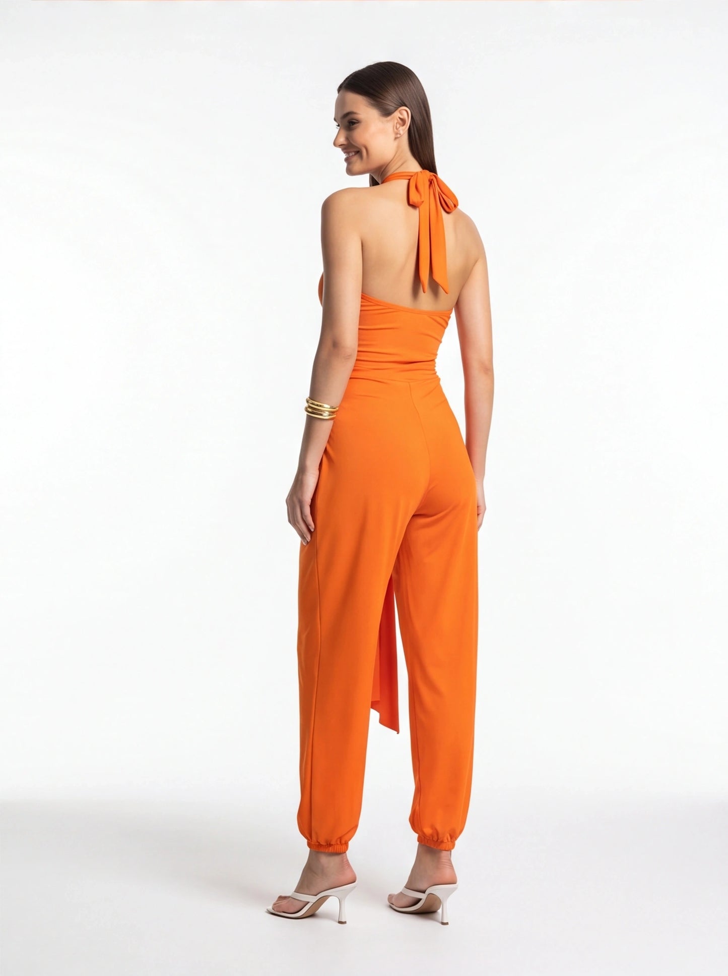 Jamota orange halter jumpsuit with back-tie neckline, sleeveless bodice, and elastic ankle cuffs on wide-leg pants.