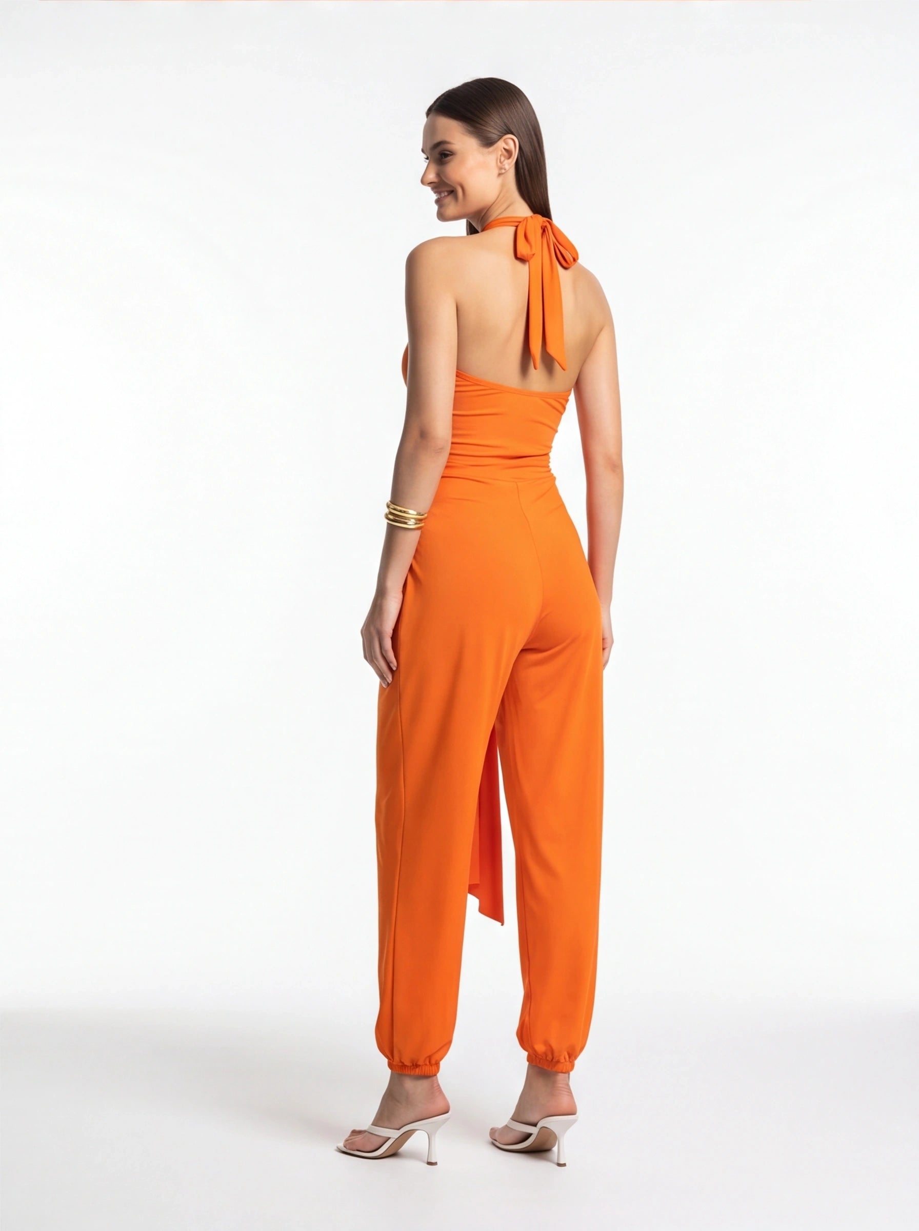Jamota orange halter jumpsuit with back-tie neckline, sleeveless bodice, and elastic ankle cuffs on wide-leg pants.