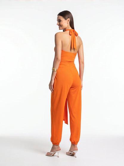 Jamota orange halter jumpsuit with back-tie neckline, sleeveless bodice, and elastic ankle cuffs on wide-leg pants.