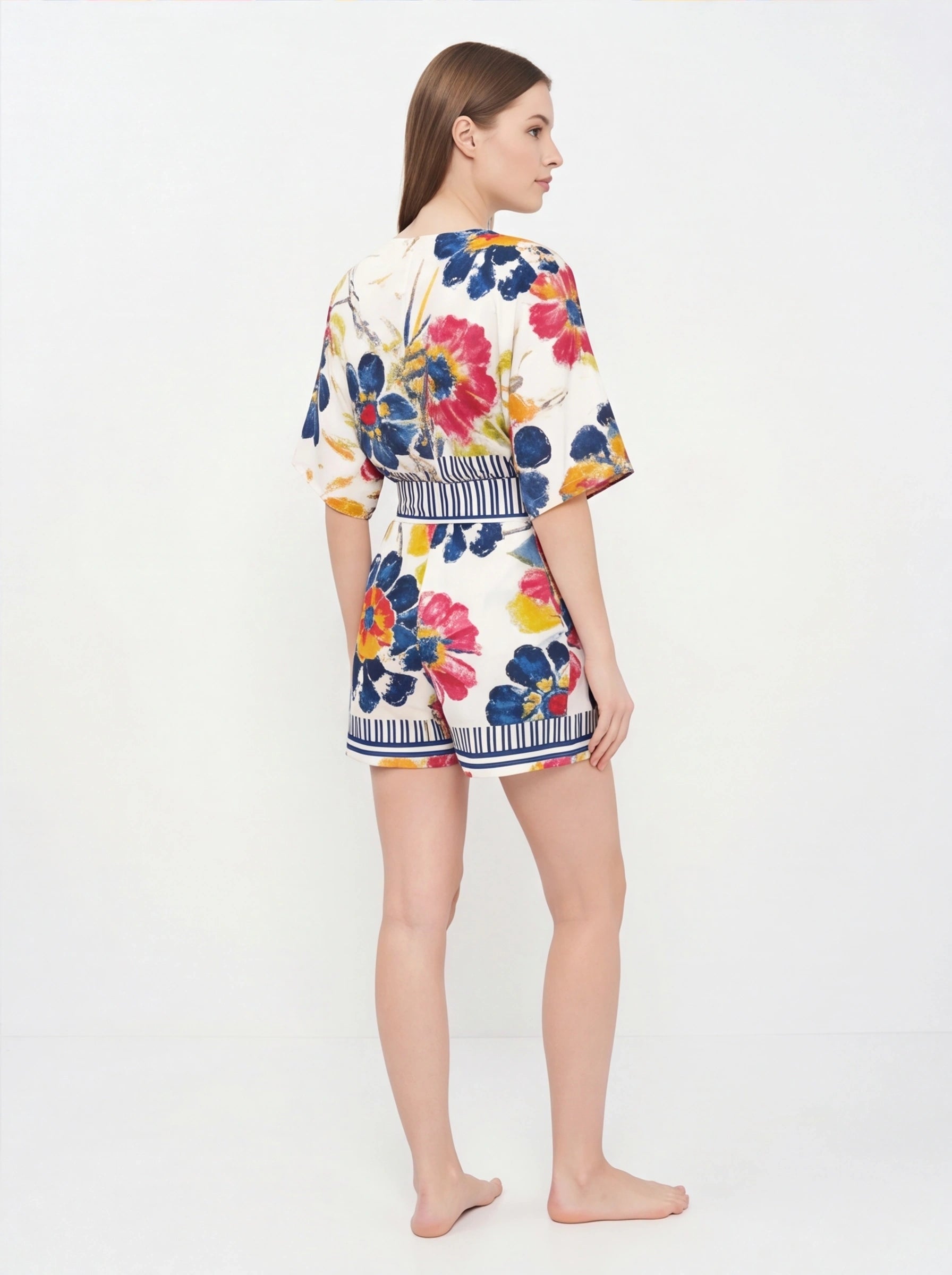 Jamota floral print romper with adjustable straps, white base and striped waistband featuring colorful flowers.