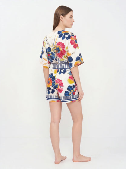 Jamota floral print romper with adjustable straps, white base and striped waistband featuring colorful flowers.