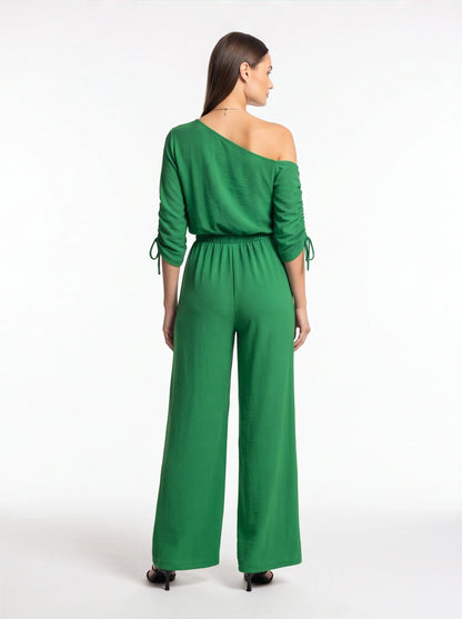 Jamota green wide-leg jumpsuit with one-shoulder neckline and long sleeves with tie cuffs.