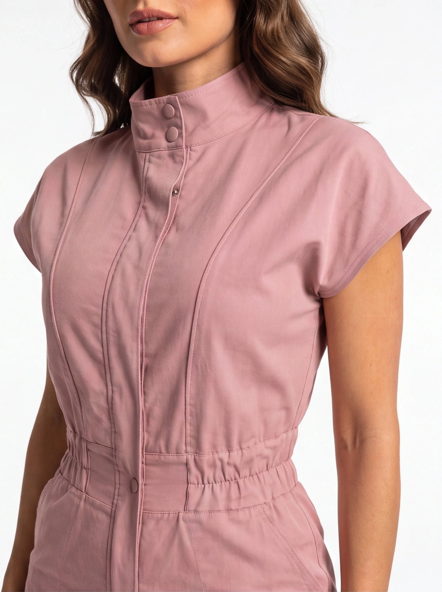 Jamota pink jumpsuit with high-neck collar, pockets, snap buttons, and waist seam details.