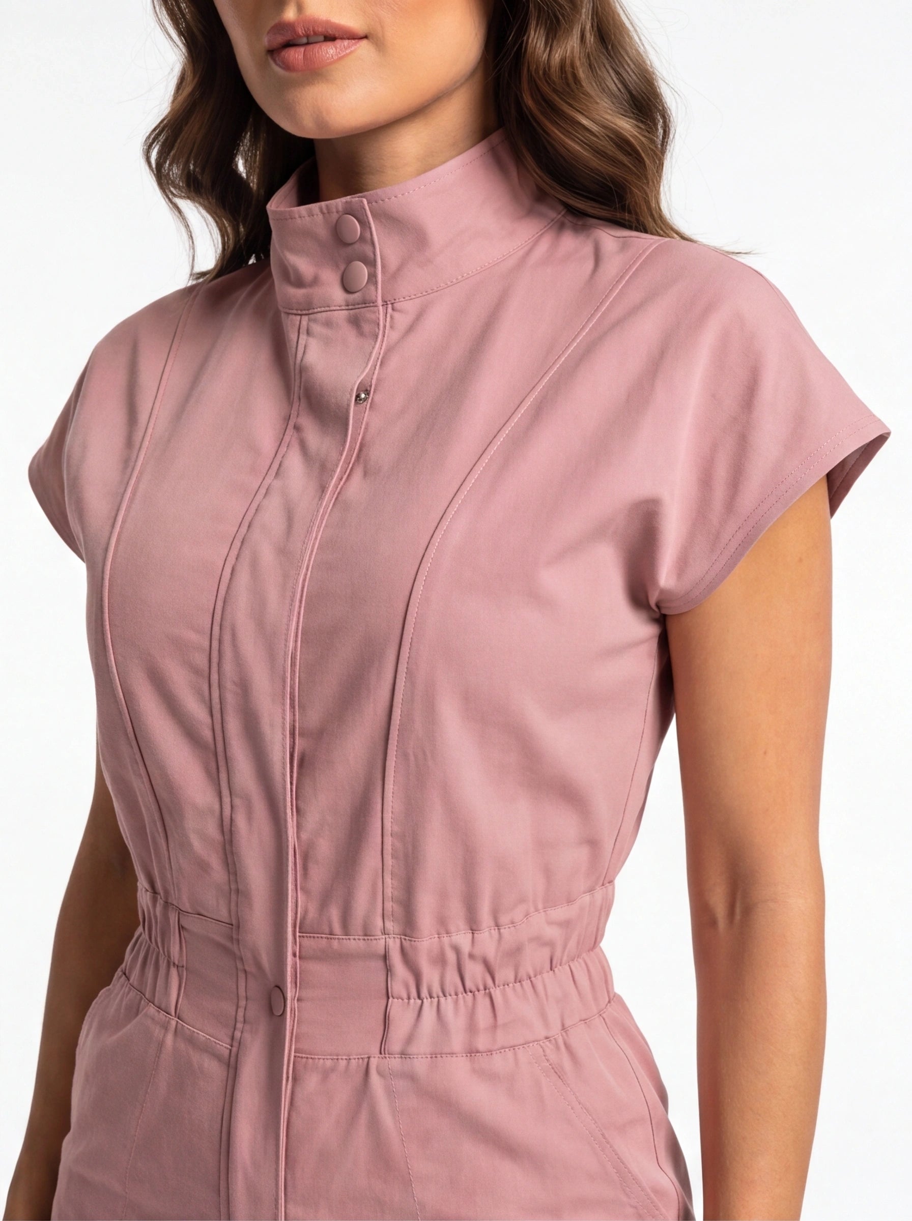 Jamota pink jumpsuit with high-neck collar, pockets, snap buttons, and waist seam details.