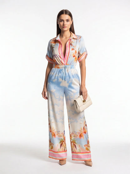Jamota tropical print jumpsuit with light blue palm motif, pink placket, rolled sleeves and elastic drawstring waist.