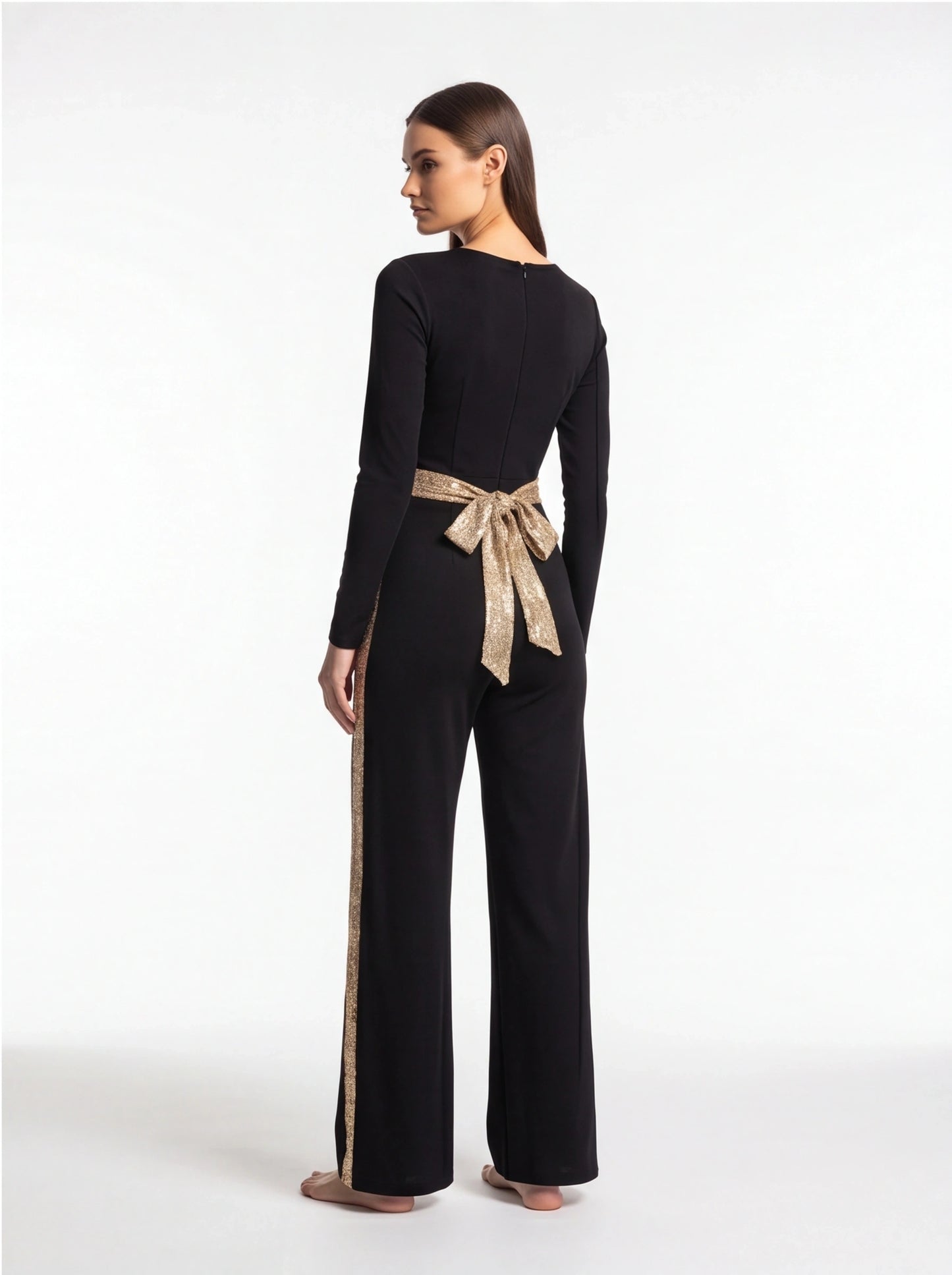Jamota black jumpsuit with gold sequin belt tied in a bow at the waist, long sleeves and wide-leg pants