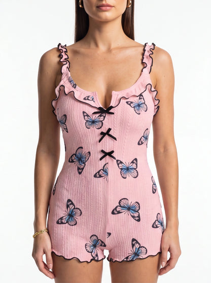 Jamota pink women's sleepwear onesie with butterfly print, ruffled straps, black trim, and front bow accents.